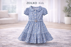 Mädchen trägt ein blaues ZEILKO-Kids Sommerkleid mit Blumenmuster und Haarband beim Spielen im sonnigen Park
